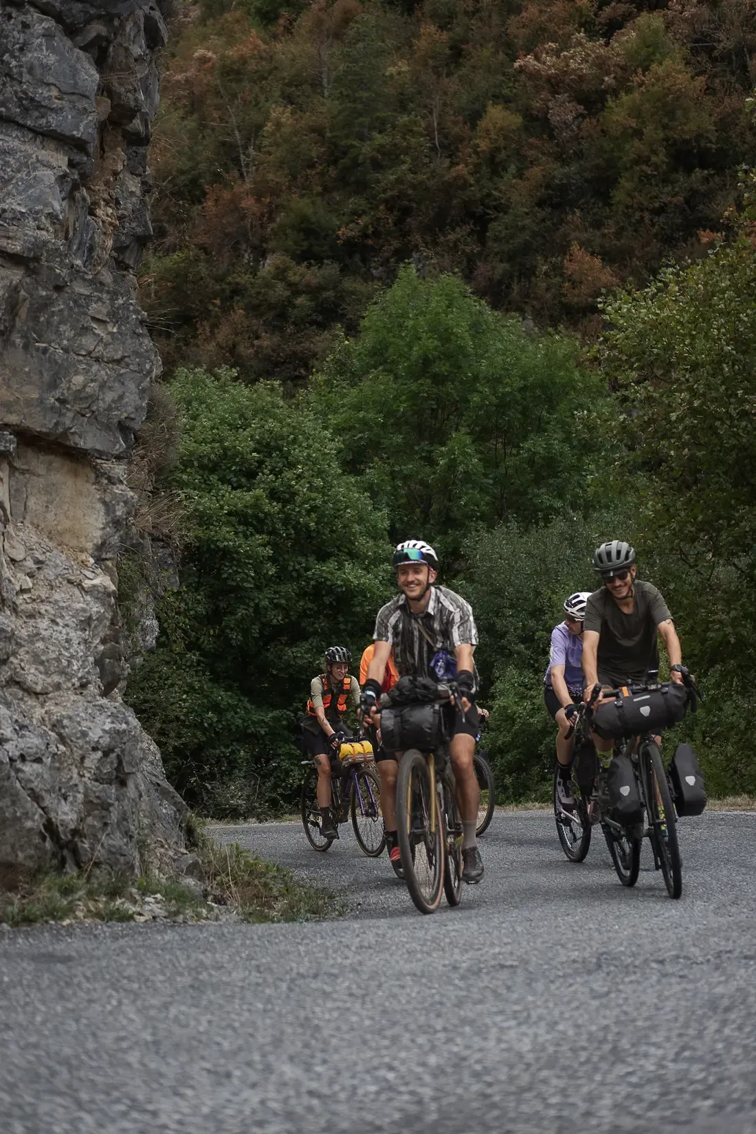 Quatre cyclotouristes avec sacoches sur une route de montagne